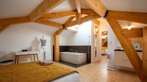 A bedroom with a bed, a desk, a mannequin, and a bathroom with a bathtub. - La Métairie du Clos Saint Louis (Montreal)