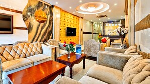 A luxurious hotel lobby with plush seating, a large wall-mounted TV, and a decorative wall with a golden pattern. - HANZ MinhVy Hotel (Ho Chi Minh City)