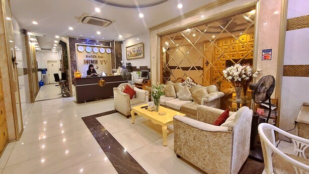 A hotel reception area with a reception desk, seating area, and a decorative wall. - HANZ MinhVy Hotel (Ho Chi Minh City)