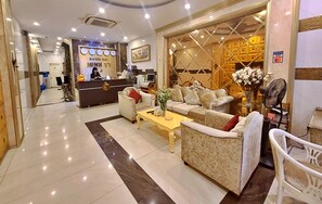 A hotel reception area with a reception desk, seating area, and a decorative wall. - HANZ MinhVy Hotel (Ho Chi Minh City)