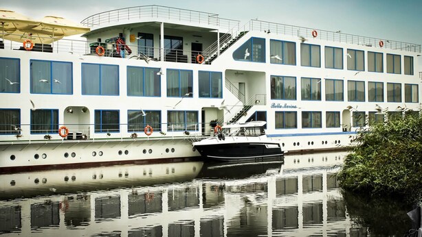 A large, multi-deck cruise ship with balconies and windows, named 'Bella Marina'.