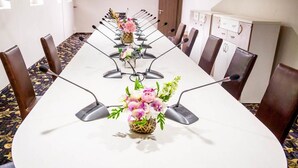 A conference room with a long table, multiple chairs, and microphones.