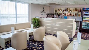 A hotel lobby with a reception desk, seating area, and a bar with various liquor bottles.
