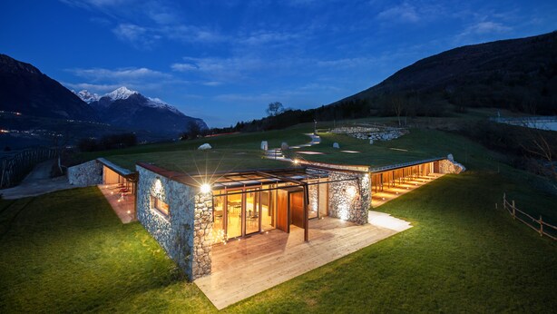 A modern house with a stone exterior, large windows, and a wooden deck. - Casariga (Comano Terme)