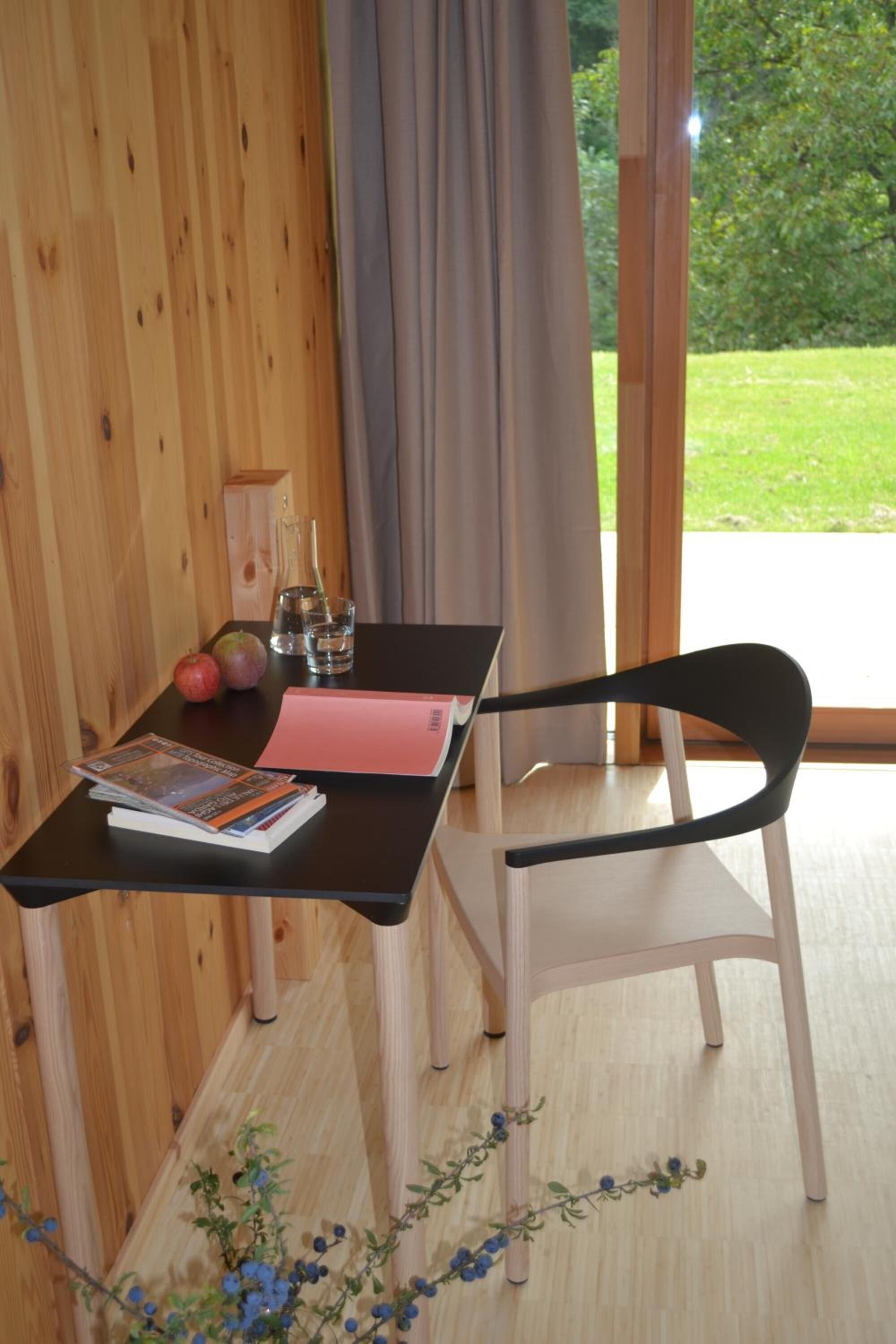 Un interno in legno con tavolo, sedia e vista sull'esterno.