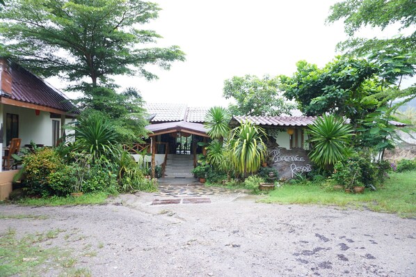 A resort entrance with a tiled roof, a staircase leading to the main building, and lush greenery surrounding the property.
