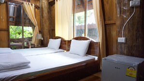 Una habitación de madera con dos camas, un refrigerador pequeño y una ventana con cortinas.