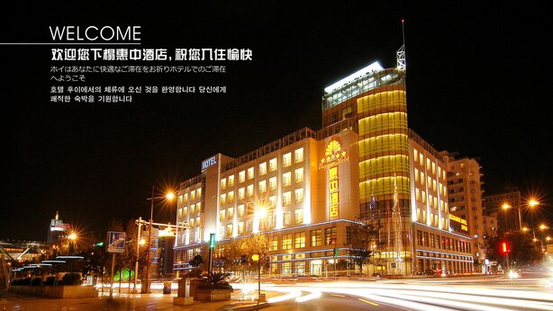 A hotel with multiple floors, illuminated windows, and a prominent sign. - Elegance Hotel Tianjin (Tianjin)