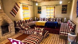 A traditional room with patterned bedding, a fireplace, and a drum. - Dar Mari (Taouz)