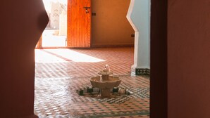 An arched doorway leading to a room with a tiled floor and a wooden door. - Dar Mari (Taouz)