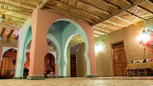 An interior with a thatched roof, arches, and a tiled floor. - Dar Mari (Taouz)