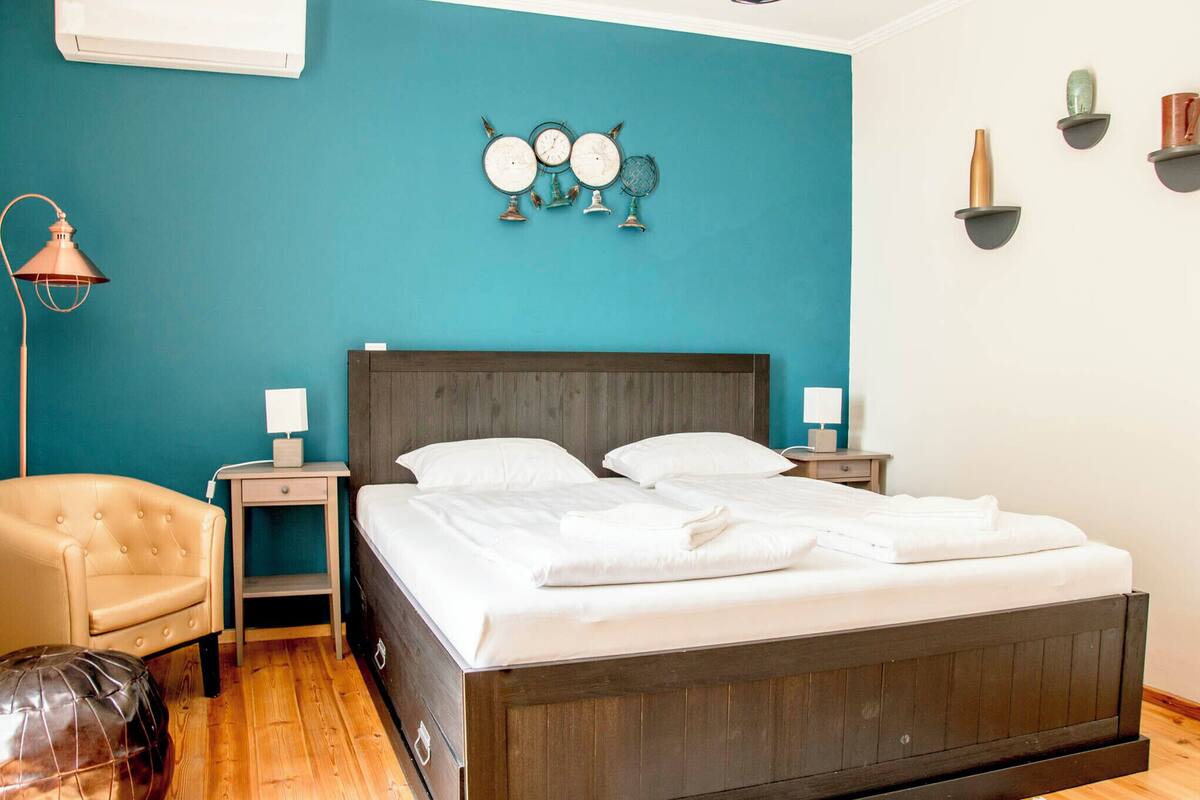 Une chambre à coucher avec un lit en bois, deux tables de chevet, une lampe, une chaise et des éléments de décoration murale.