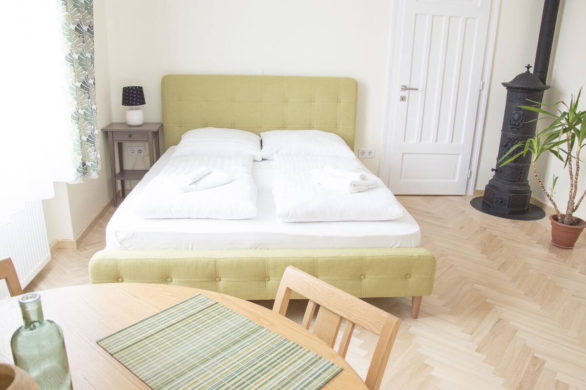 Une chambre à coucher bien rangée, avec un lit, une table de chevet, une lampe et une plante en pot.