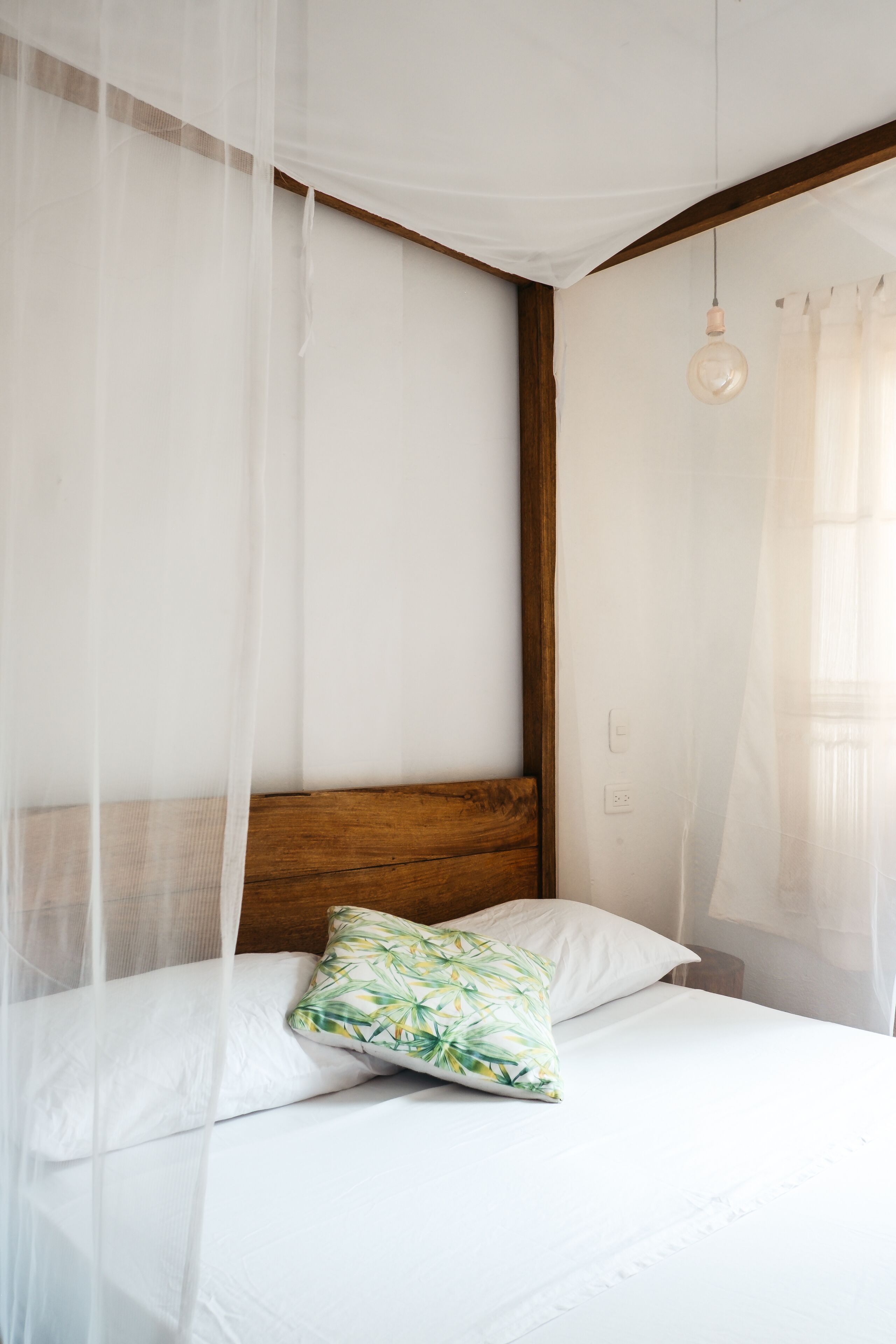 Ein Bett mit Holz-Kopfteil, weißer Bettwäsche und einem einzelnen Zierkissen.