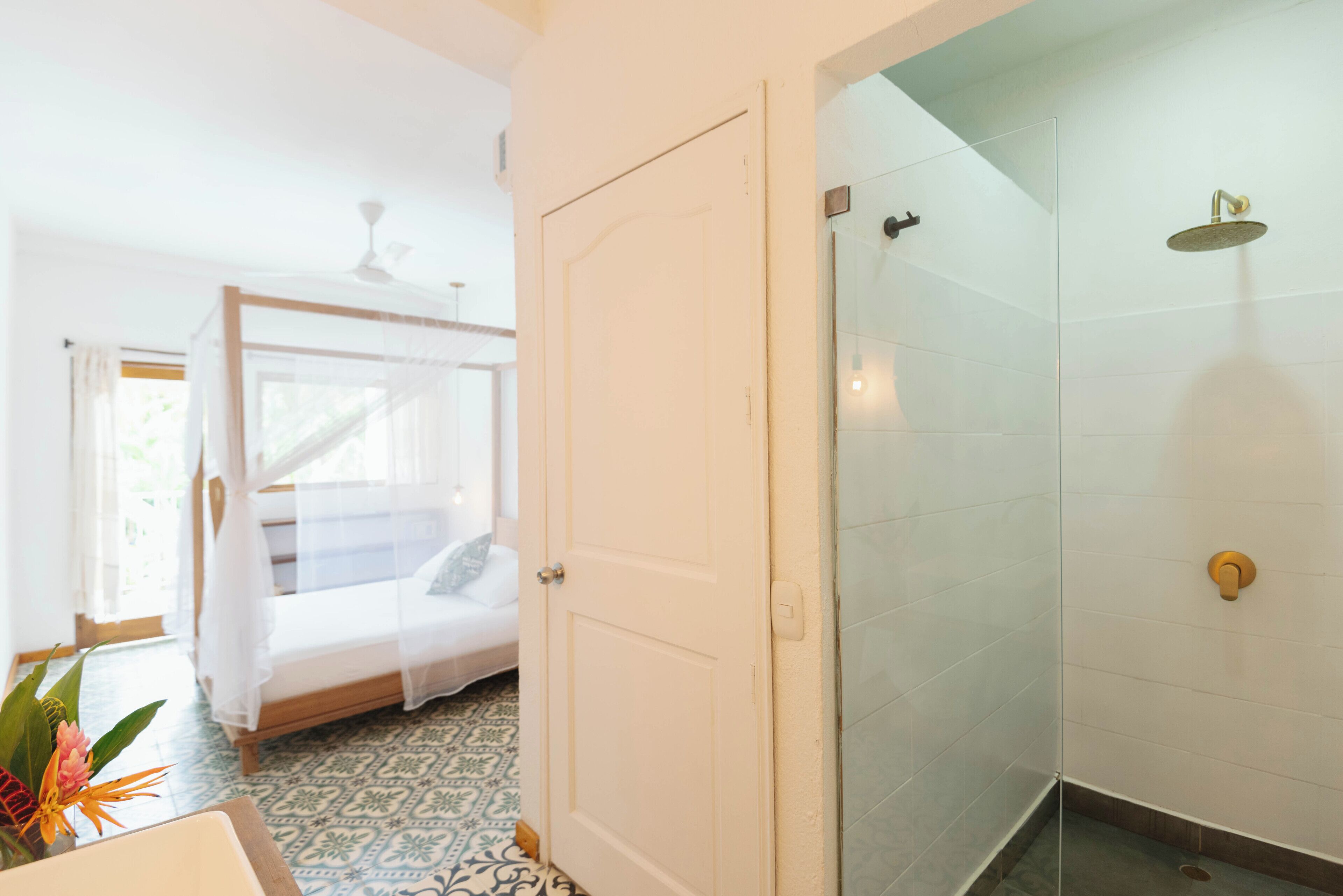 Una habitación con cama, zona de ducha y puerta.