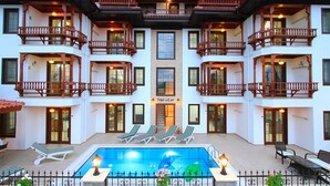 A multi-story hotel with balconies, a swimming pool, and outdoor seating. - Deger Apart (Ula)
