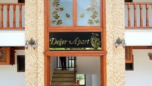 A building entrance with a wooden staircase, a sign reading "Deger Apart", and patterned columns. - Deger Apart (Ula)