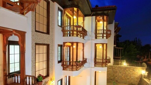 A multi-story building with balconies, a swimming pool, and outdoor seating. - Deger Apart (Ula)