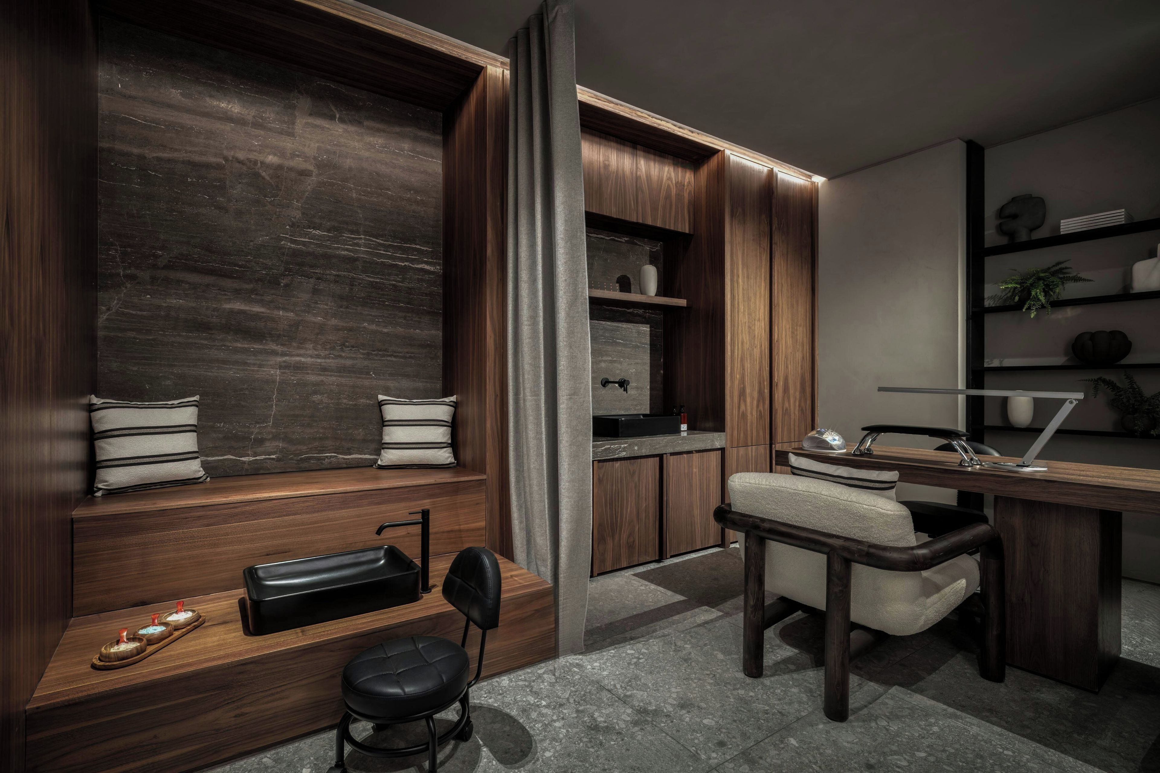A modern kitchen with dark wood cabinetry, a built-in bench with cushions, and a dining area with a chair and table.