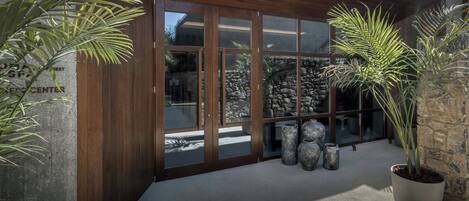 A building entrance with a wooden facade, large glass doors, and potted plants.