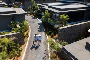 A modern hotel with a curved driveway, outdoor seating, and lush landscaping.