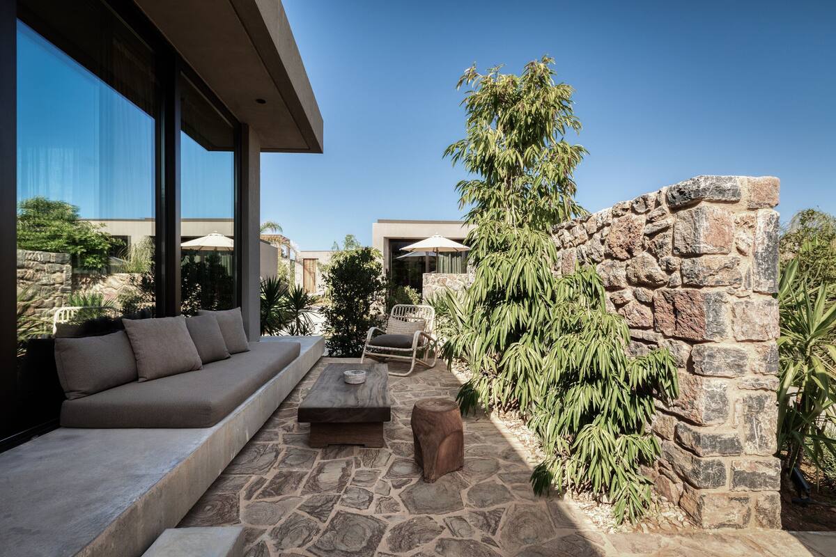 An outdoor seating area with a stone wall, a sofa, and a table.