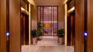 A modern hotel lobby with a marble floor, wooden paneling, and potted plants. - KuanRong Luxury Suites Hotel - Daping Times Square (Chongqing)