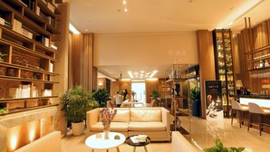 A spacious hotel lobby with a plush sofa, a coffee table, and a bar area with shelves of bottles. - KuanRong Luxury Suites Hotel - Daping Times Square (Chongqing)