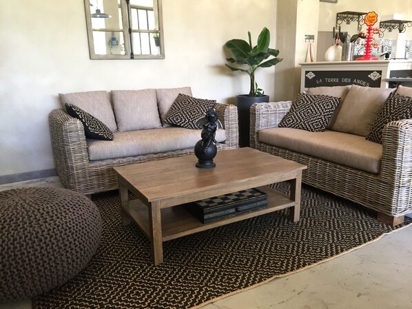 A living room with two wicker sofas, a wooden coffee table, and a patterned rug. - Le Mas Terre des Anges (Sarrians)