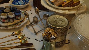 A table with various food items, utensils, and decorative plates. - Kemmare (Riposto)