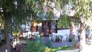 A patio area with outdoor seating and a stone wall. - Hotel Viktória Vendégház (Balatonalmadi)