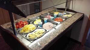 A buffet with various food items including sliced tomatoes, yellow bell peppers, and different types of cheese. - Hotel Viktória Vendégház (Balatonalmadi)