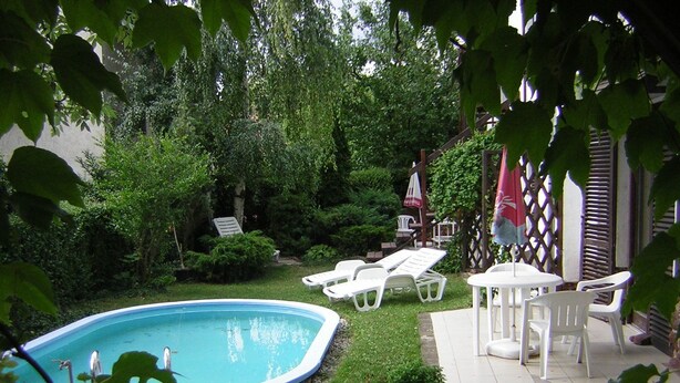 A backyard with a swimming pool, lounge chairs, and a patio area. - Hotel Viktória Vendégház (Balatonalmadi)