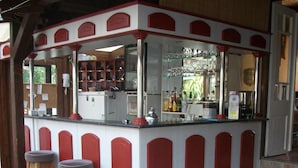 A bar area with stools and tables, a tiled floor, and a counter with various items. - Hotel Viktória Vendégház (Balatonalmadi)