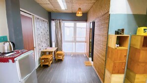 Una cocina compacta con refrigerador, una mesa de madera y una lámpara colgante.