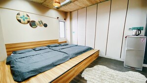Un dormitorio con una cama de madera, una alfombra blanca, un refrigerador y una pared decorada con platos.