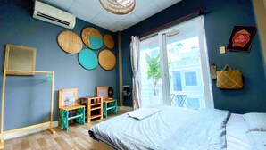 Un dormitorio con cama, repisa de madera, lámpara colgante y vista al exterior.
