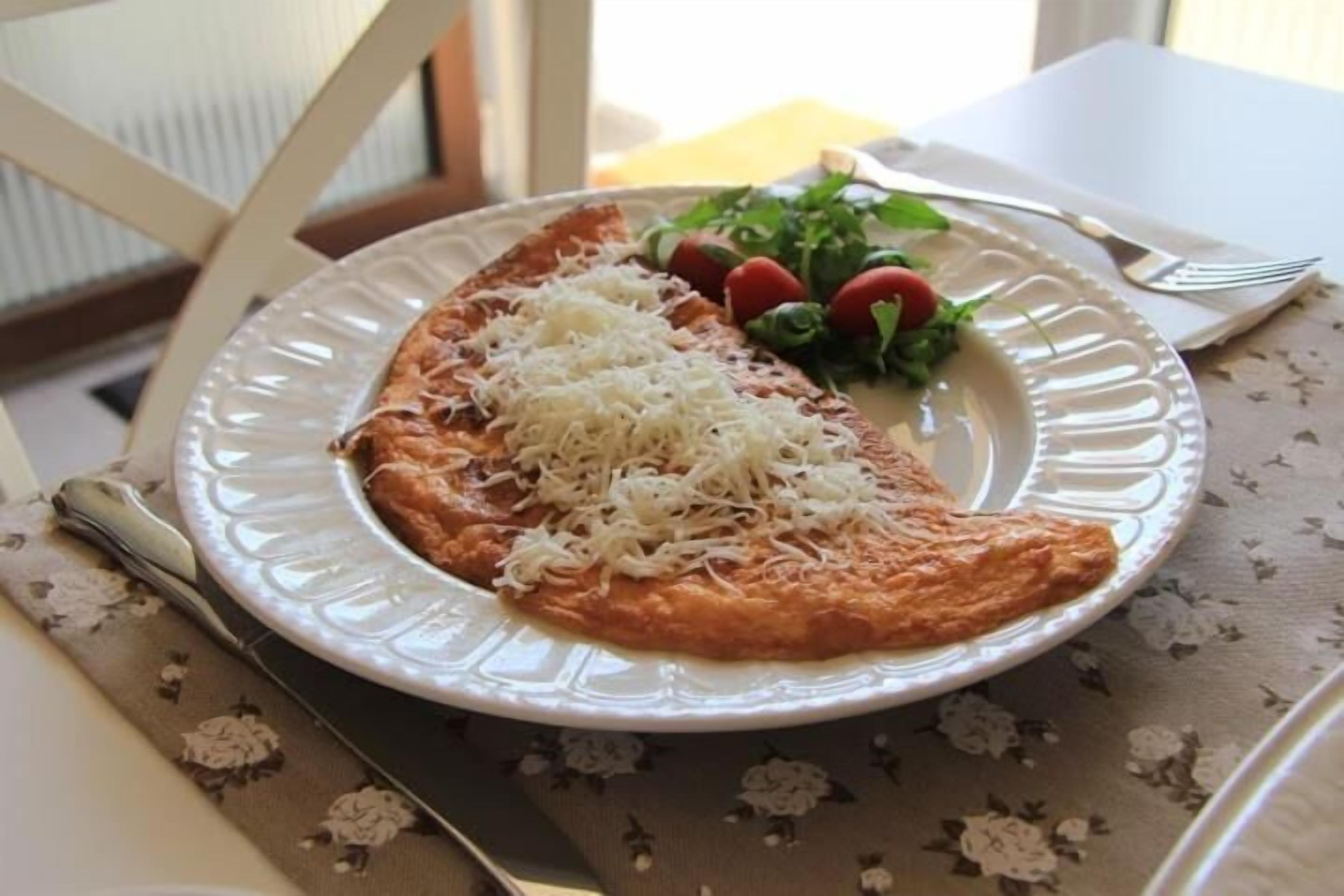A plate with a slice of pizza topped with cheese, a side salad, and cherry tomatoes.