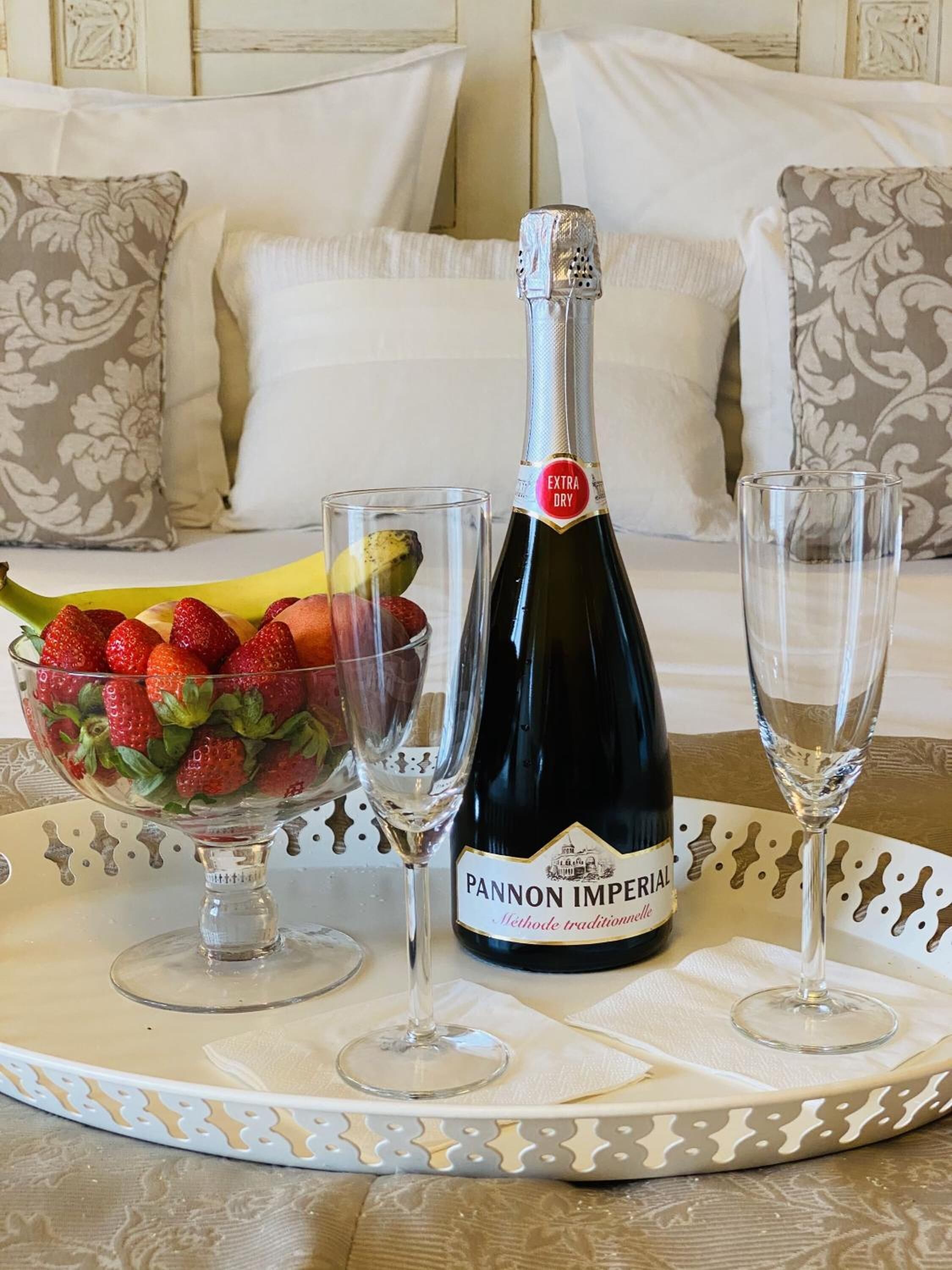 A bottle of Pannon Imperial wine, a bowl of strawberries, and two wine glasses on a tray.