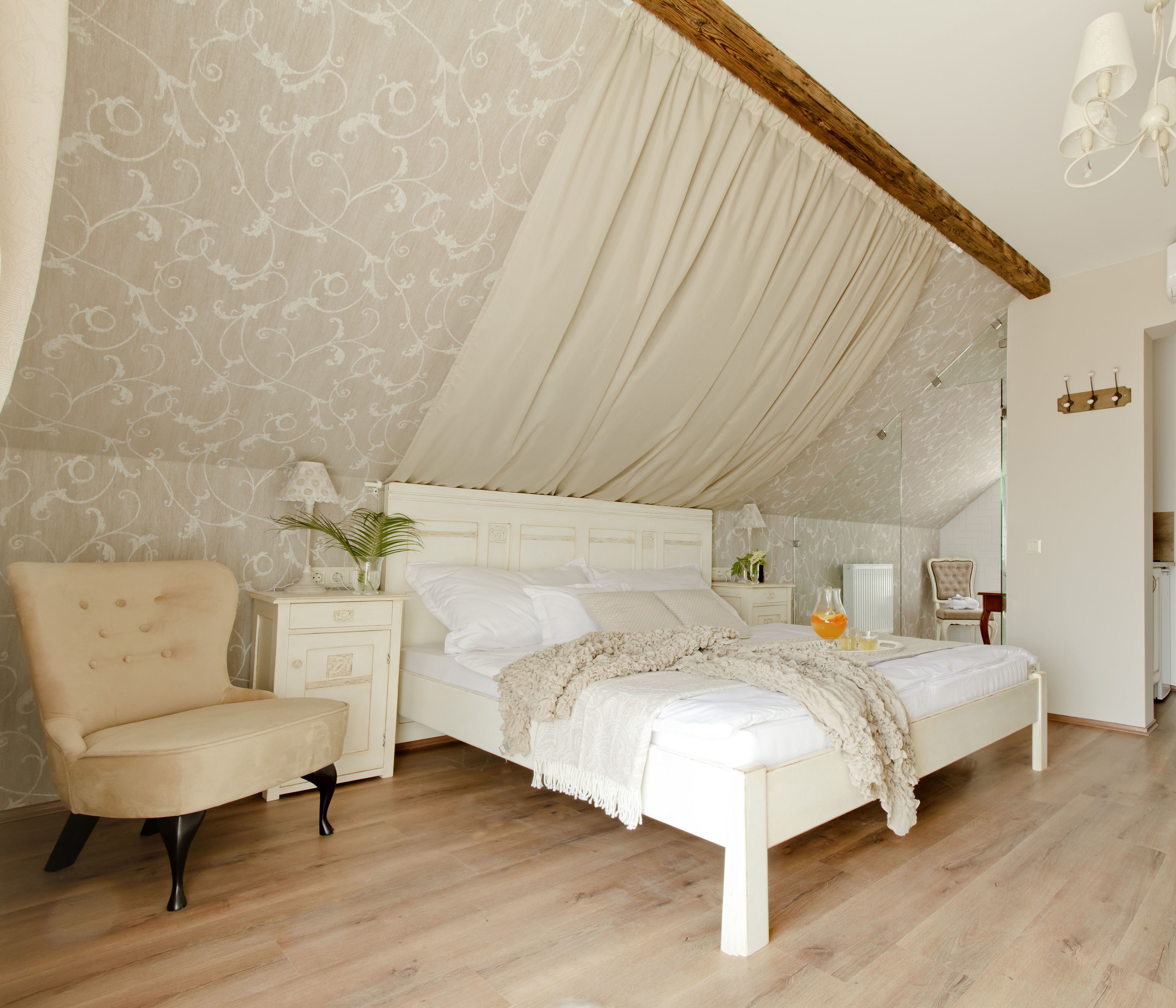A bedroom with a bed, a chair, a nightstand, a lamp, and a mirror.