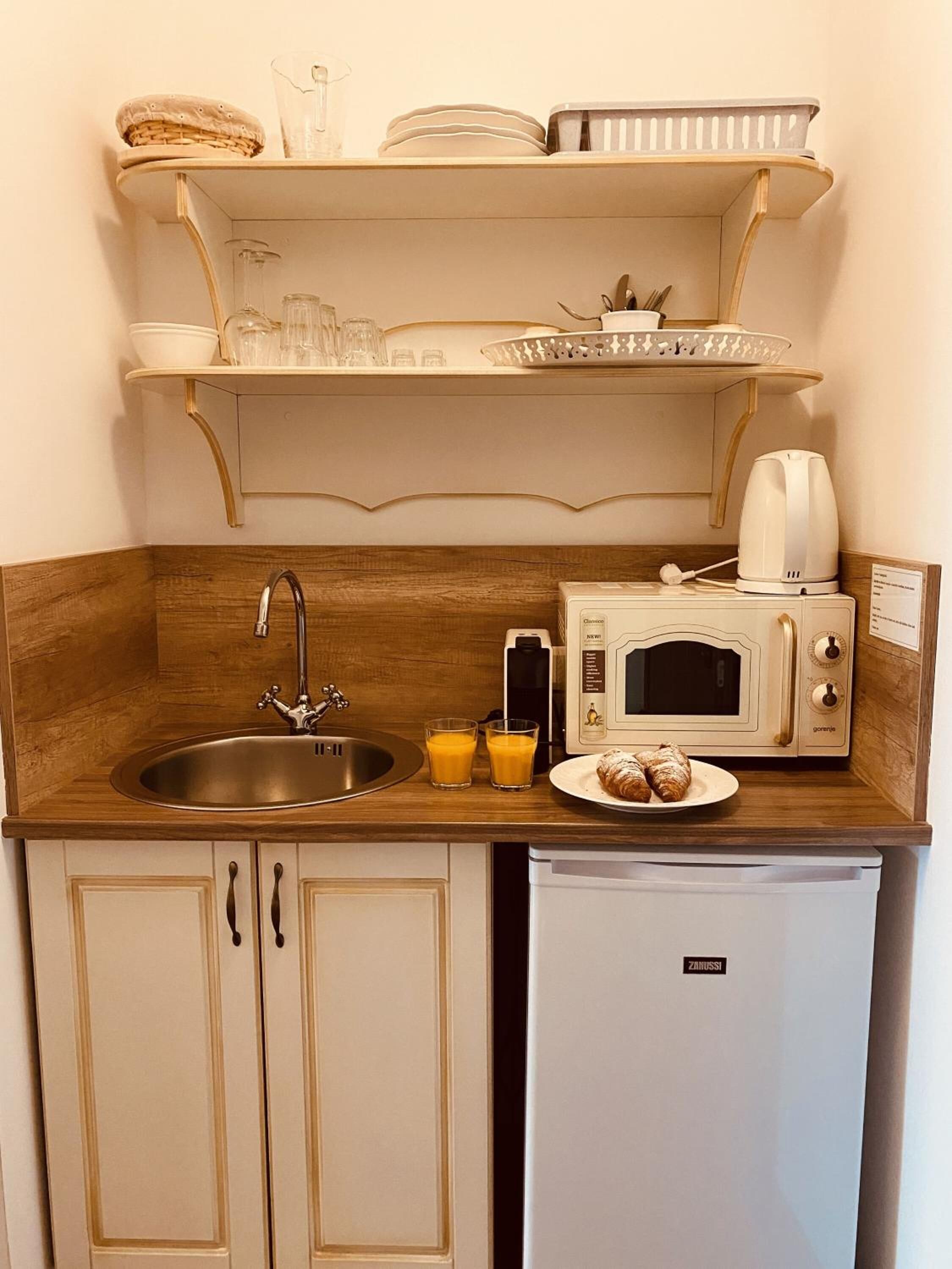 A compact kitchenette with a sink, a microwave, a coffee maker, and a small refrigerator.