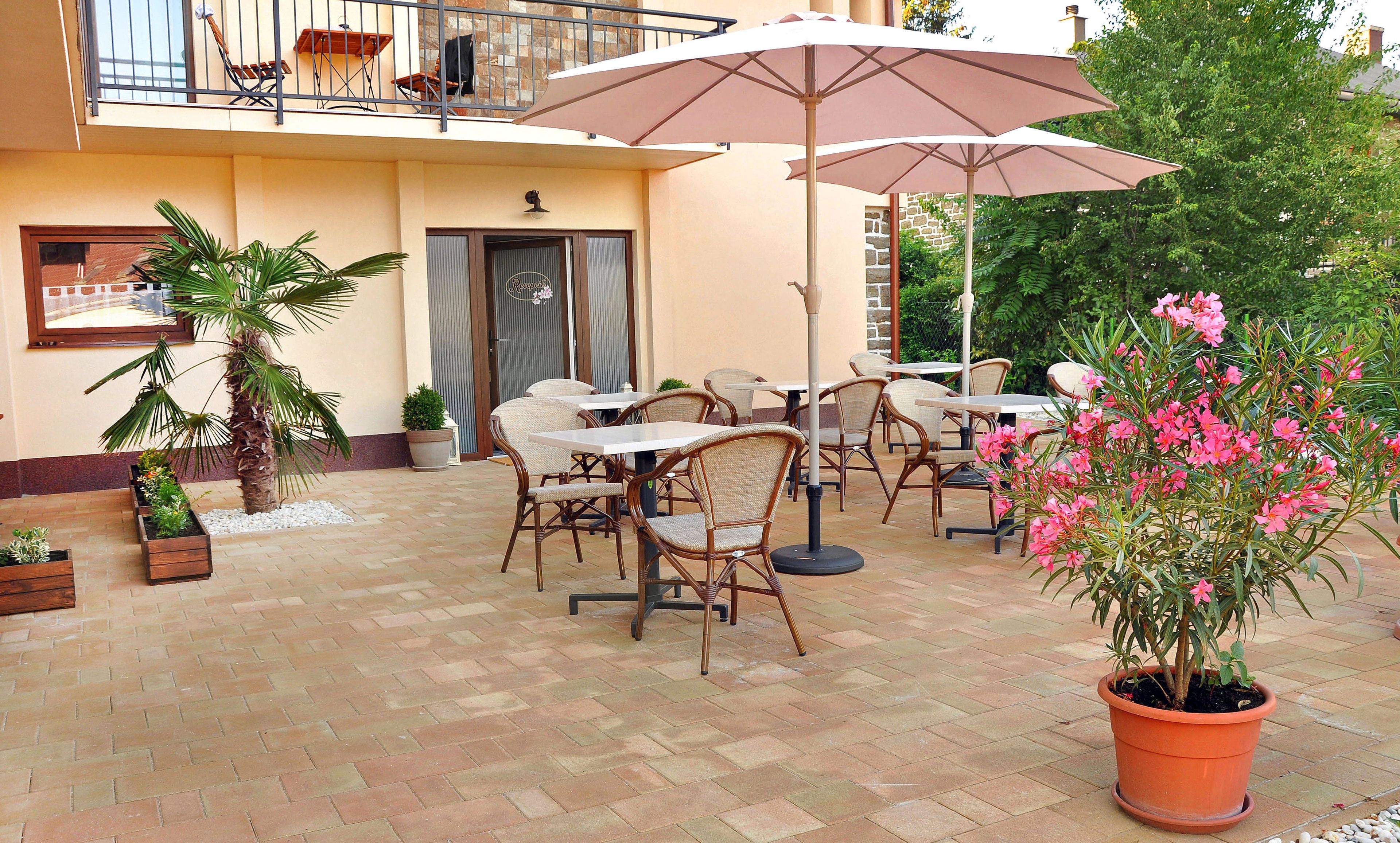 An outdoor patio with wicker furniture, potted plants, and umbrellas.