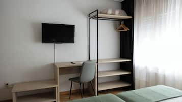 Una habitación con literas, un escritorio con silla, un televisor montado en la pared y una ventana con cortinas.