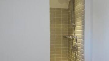 A shower with a glass enclosure, a handheld showerhead, and a wall-mounted faucet.