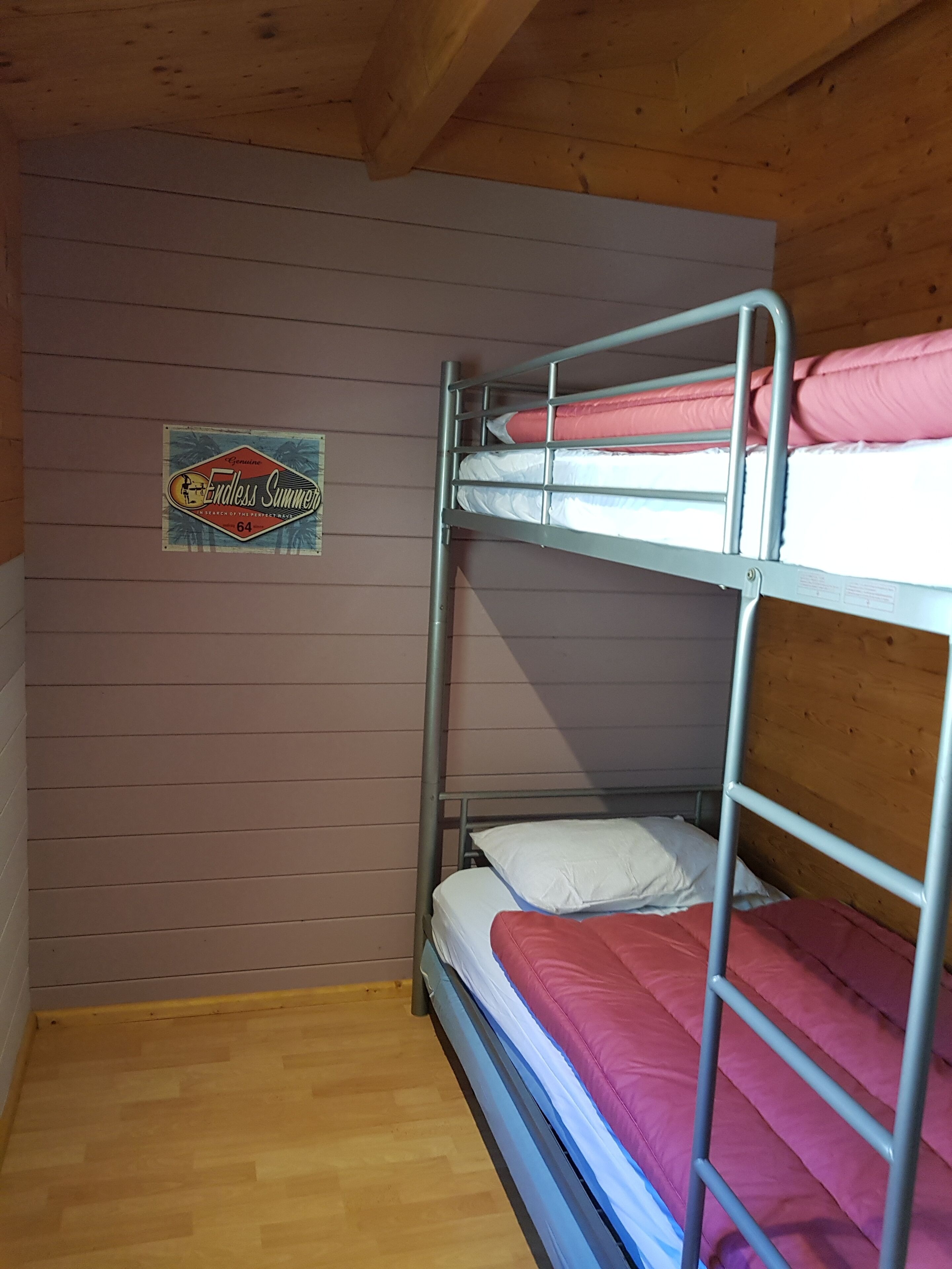 A bunk bed room with a wooden ceiling and a sign on the wall.