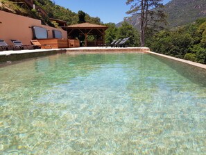 Una piscina cristalina con sillas de descanso y una terraza de madera.