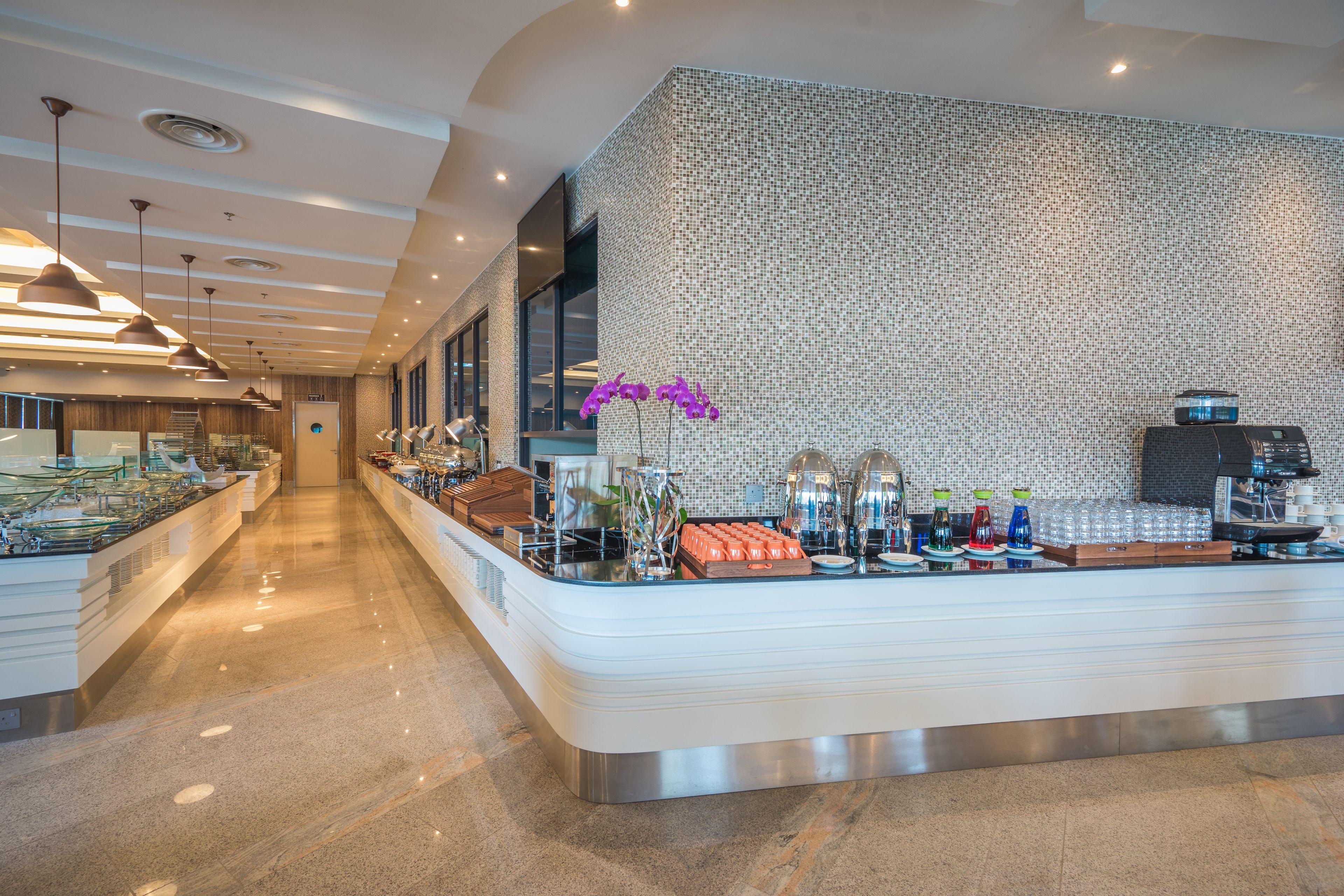 Eine moderne Hotelhalle mit einer Rezeption, einer Wand mit Muster und einer langen Theke mit Annehmlichkeiten.