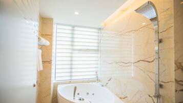 A modern bathroom with a freestanding bathtub, a showerhead, and a window with blinds.