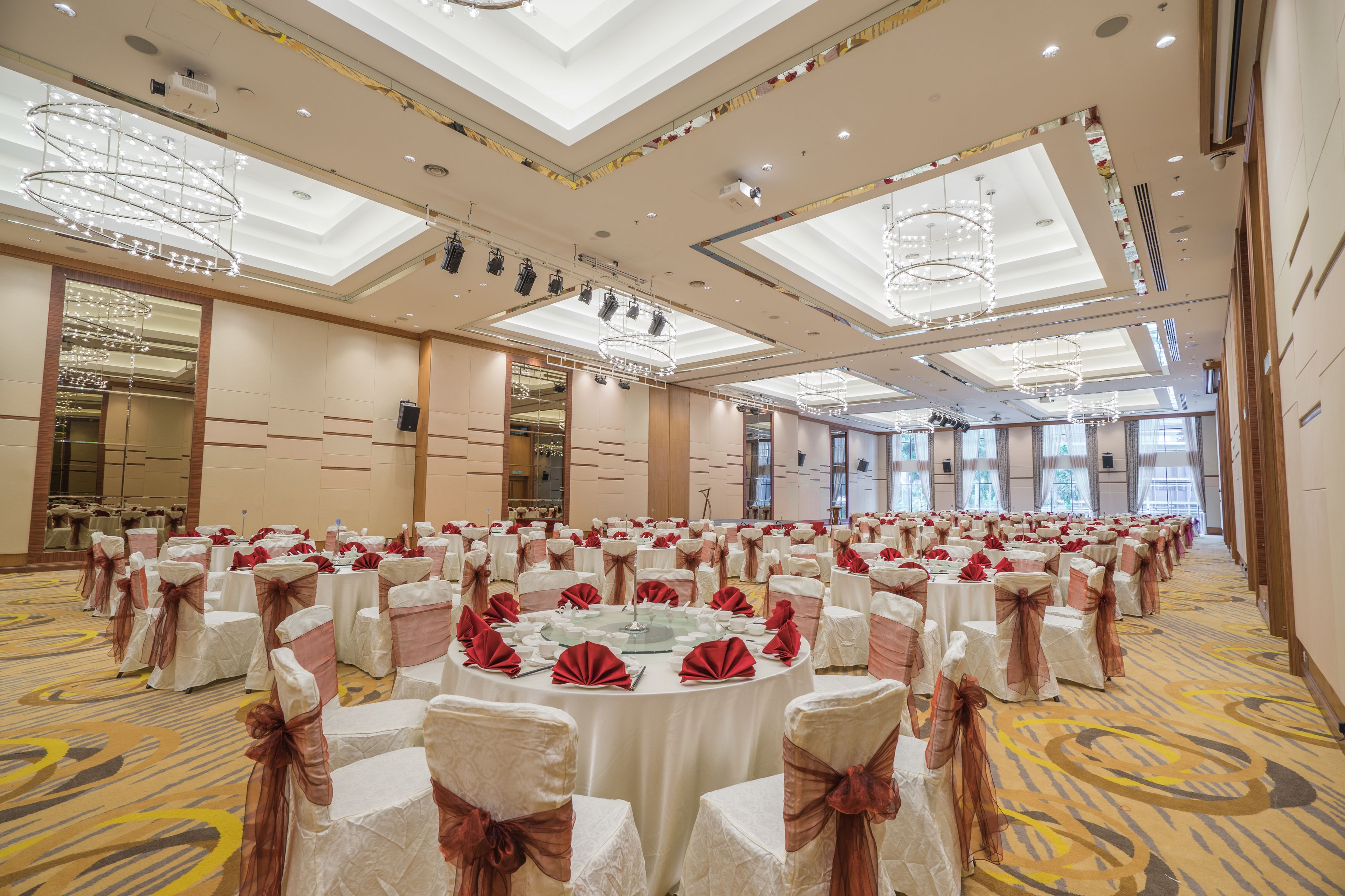 A large banquet hall with round tables, white tablecloths, and red napkins.