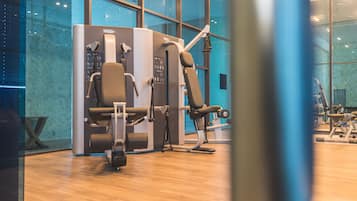 Une salle de sport équipée de machines d’exercice, dotée de grandes fenêtres et d’un plancher en bois.